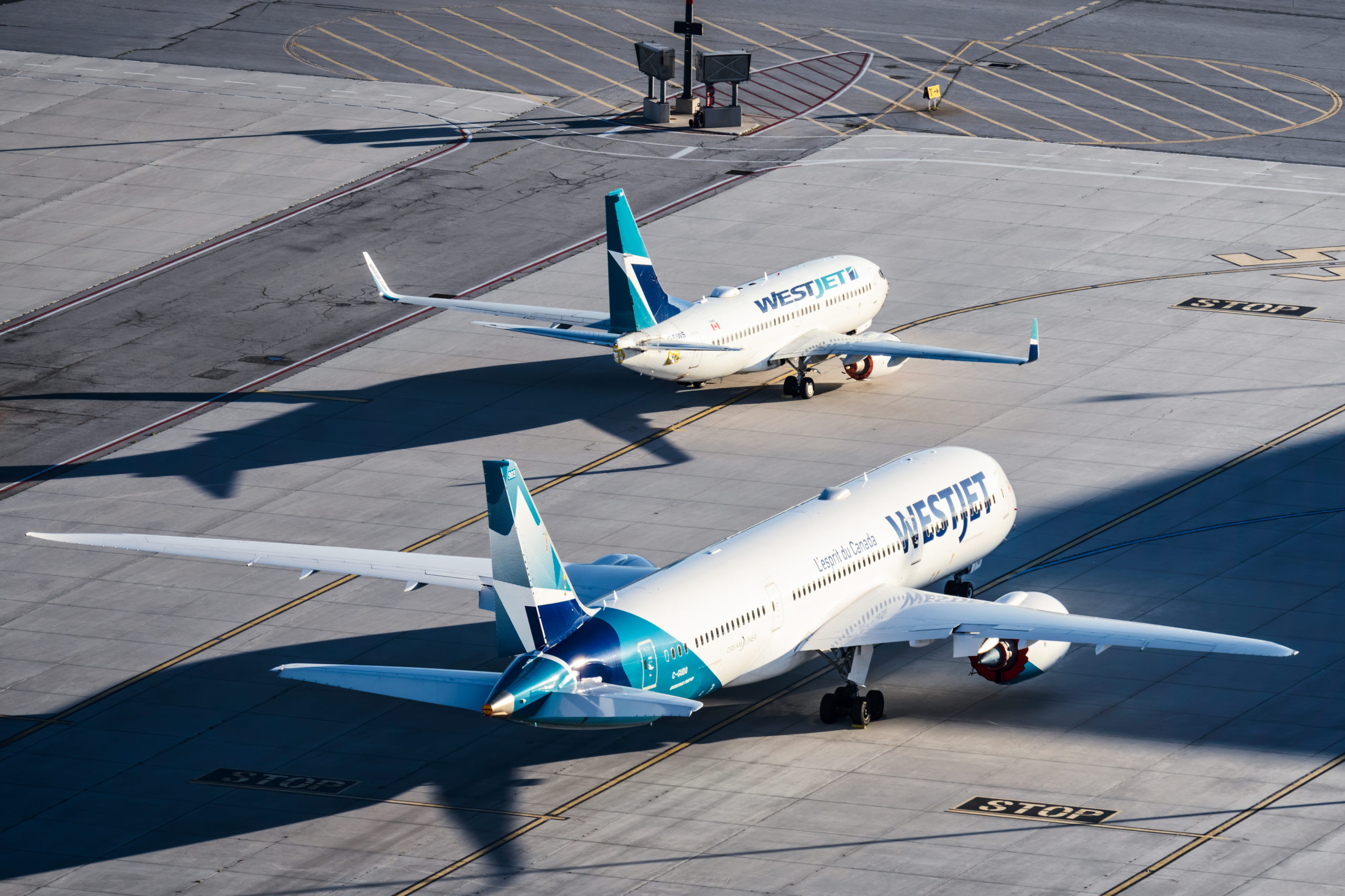 Two WestJet style airplanes getting ready to take off